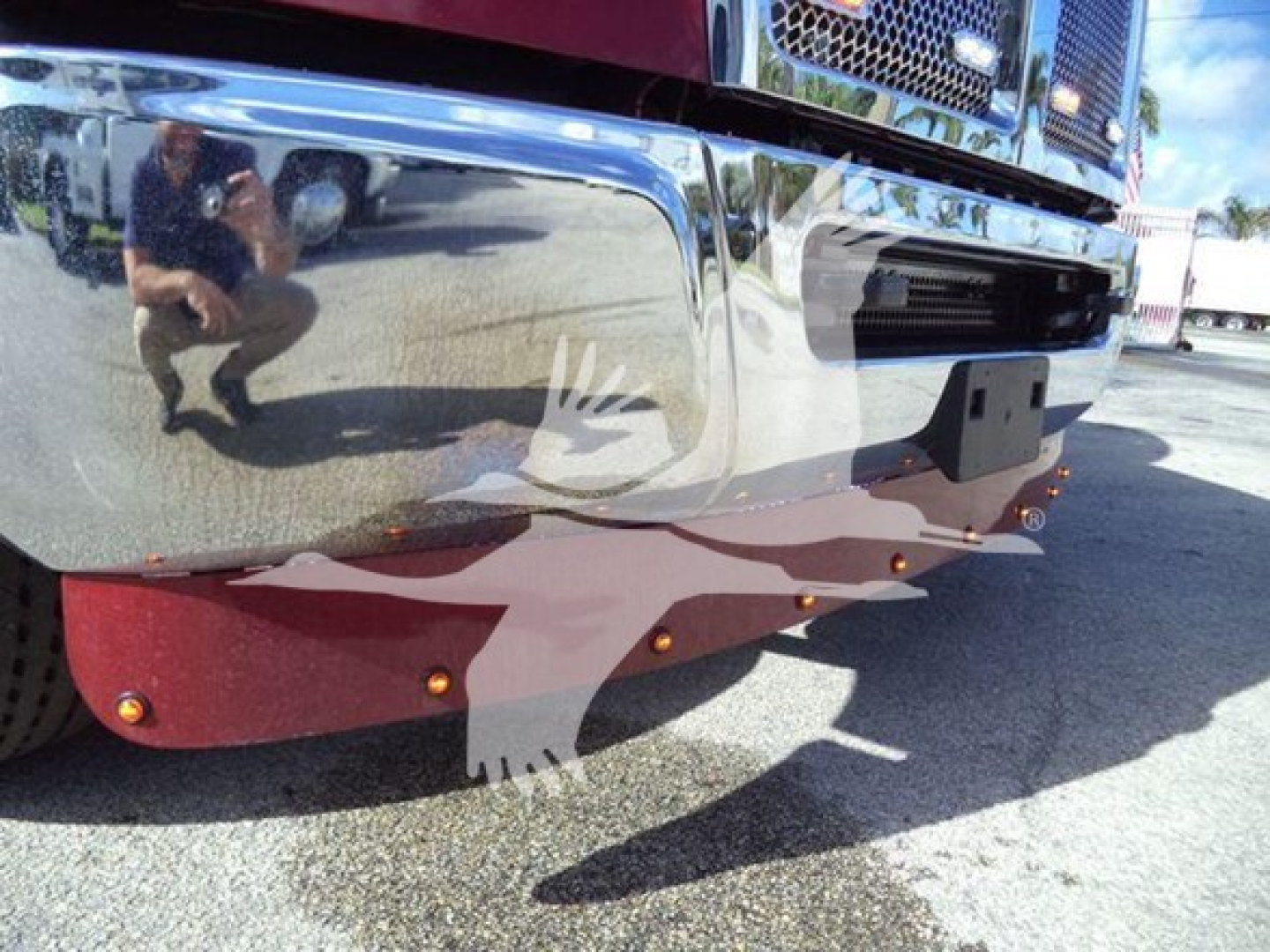 Front bumper of a 2025 Kenworth T280 rollback truck showing chrome bumper, red skid plate, and reflective surface.