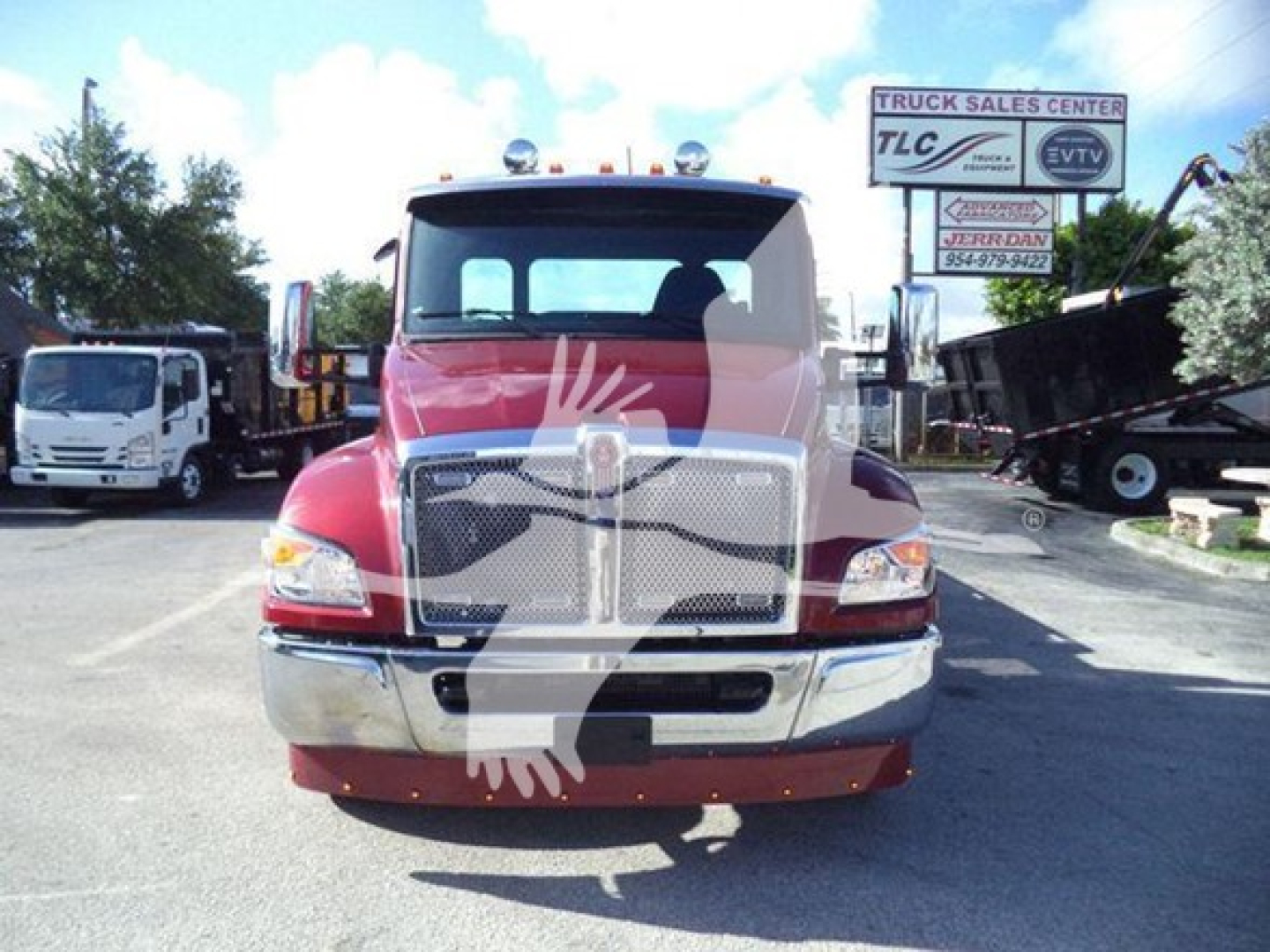 Kenworth T280 rollback truck front view showing chrome grille and bumper, red cab, clear headlights, dealership lot in background.