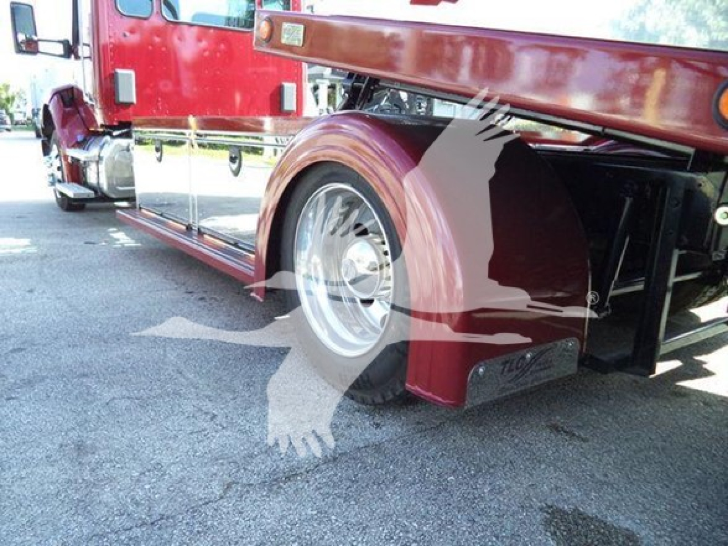 Kenworth T280 rollback truck side view showing rear wheel, red paint, chrome wheel, and loading equipment undercarriage.