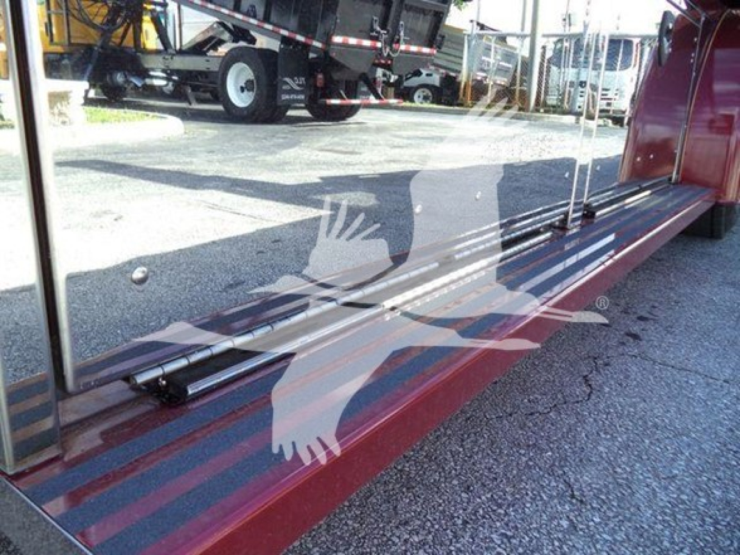 Rear view of a red rollback truck showing a reflective surface with a logo of a bird and text overlays; no legible model text visible.