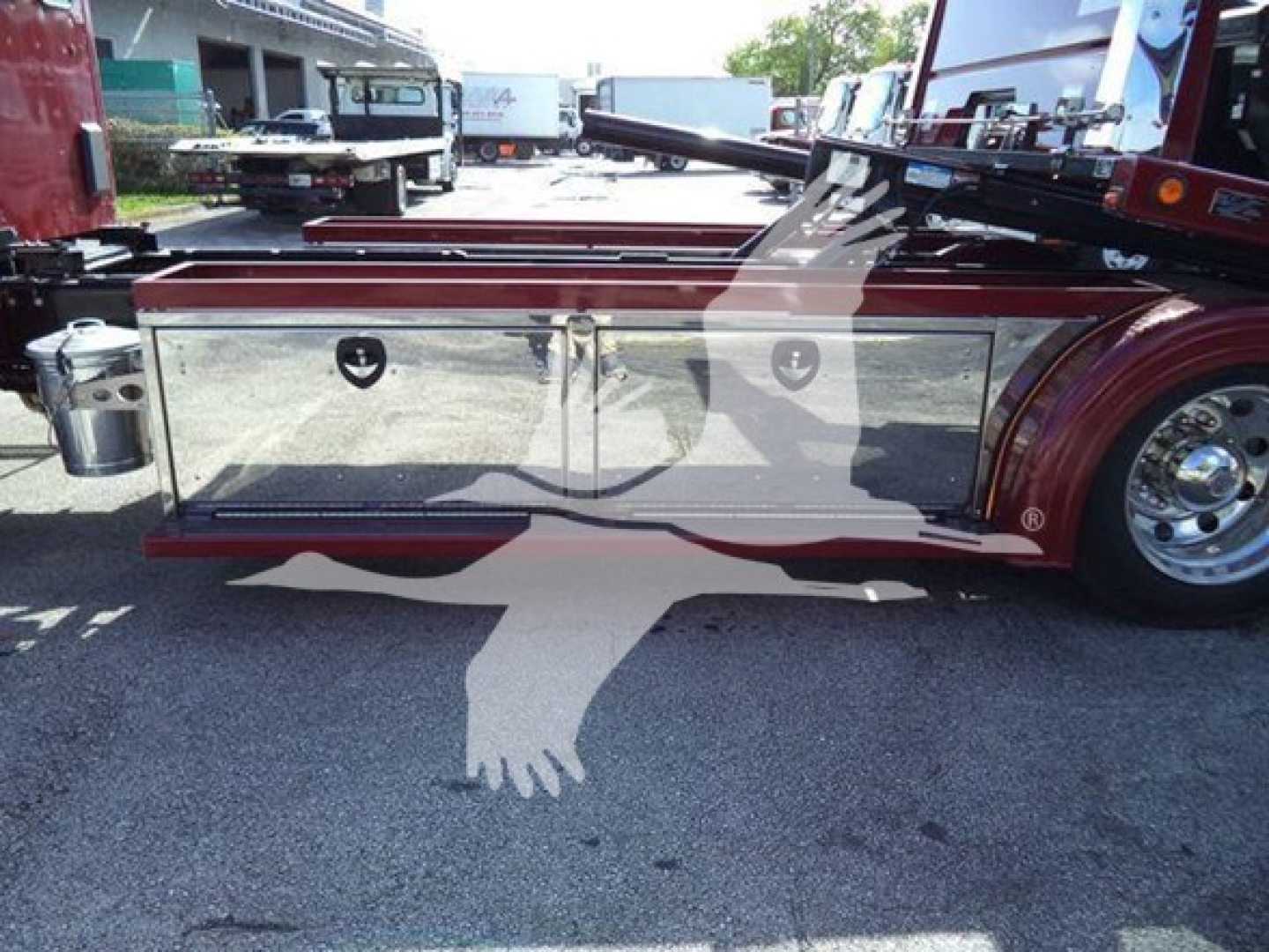 Kenworth T280 rollback truck side view showing chrome diamond plate storage compartments and toolbox along the frame with wheel and body reflectors.
