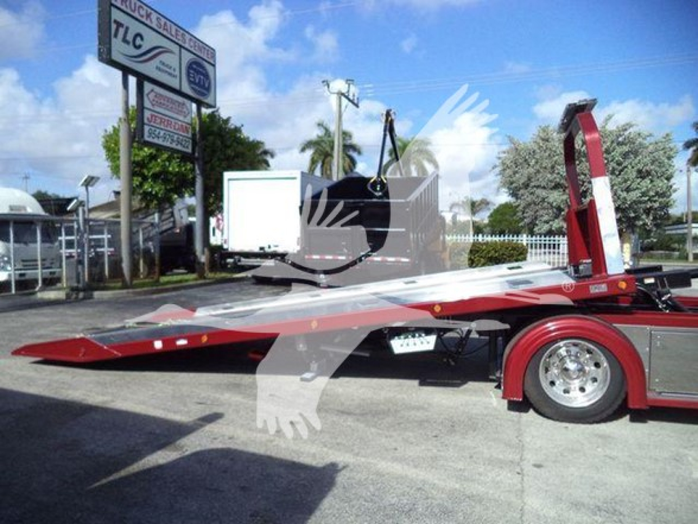 Kenworth T280 rollback truck with a long red tow bed extended, chrome wheels, and hydraulic winch assembly visible; rear wheels and platform tilted up.