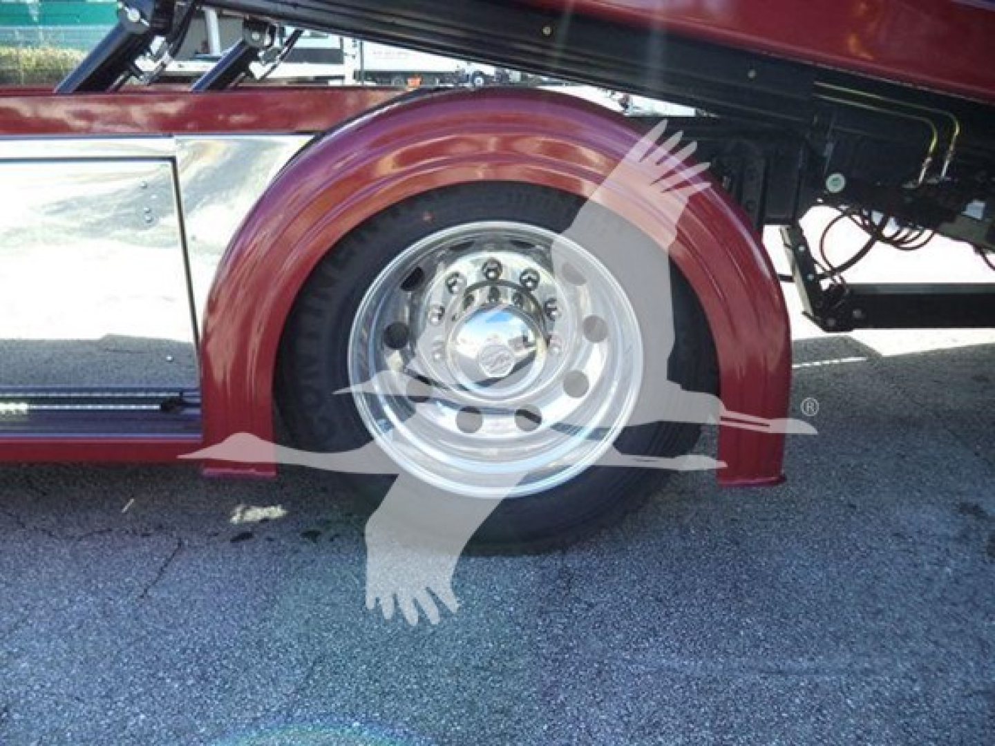 Wheel and fender of a Kenworth rollback truck showing polished steel wheel and red body.