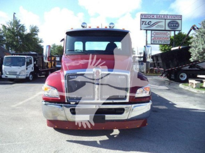 Kenworth T280 rollback truck front view showing chrome grille and bumper, red cab, clear headlights, dealership lot in background.