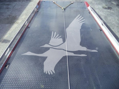 Roll-back truck bed or loading platform with textured metal surface and large bird graphic visible.