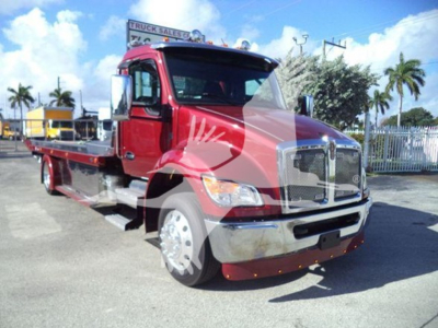 Kenworth T280 rollback truck in red with chrome grille and flatbed, front view showing wheel, cab, and towing bed.