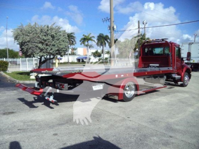 Kenworth T280 rollback truck in yard showing flatbed tow body with red cab and equipment.