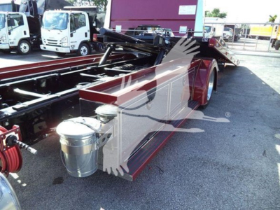 Kenworth T280 rollback truck showing fuel tanks and chassis with purple equipment in background.