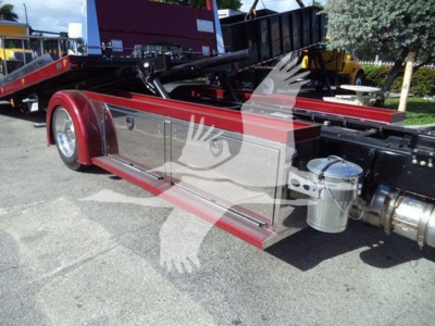 Kenworth T280 rollback truck side view showing silver storage compartments along red chassis and chrome fuel tank.