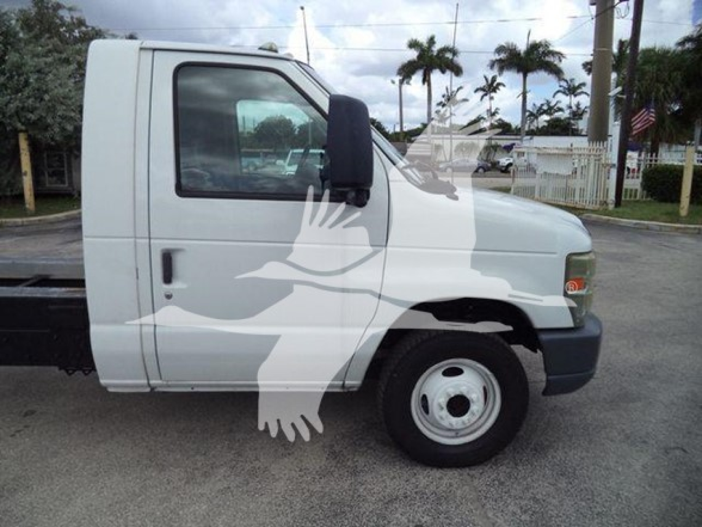 Ford E450 cab side view showing single front axle with standard steel wheel and black bumper, mid-2010s model, white exterior.