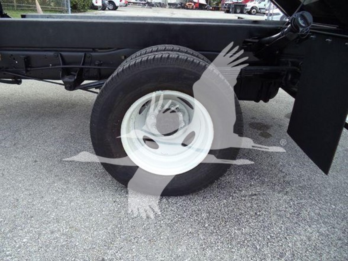 Ford E450 dump truck wheel and chassis view showing white steel wheel and tire with black undercarriage components.