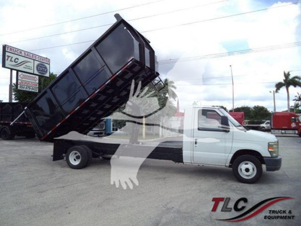  Ford E450 dump truck with raised dump bed in a dealership lot showing a white cab and black dump body.