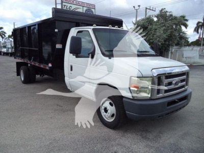 Ford E-450 dump truck at an outdoor lot showing the cab and black dump body with a white front, VIN 1FDXE4FS1BDA83803.