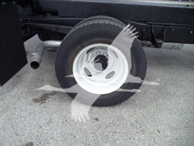 Ford E450 dump truck wheel and exhaust visible; side of chassis with tire, white wheel, exhaust pipe.