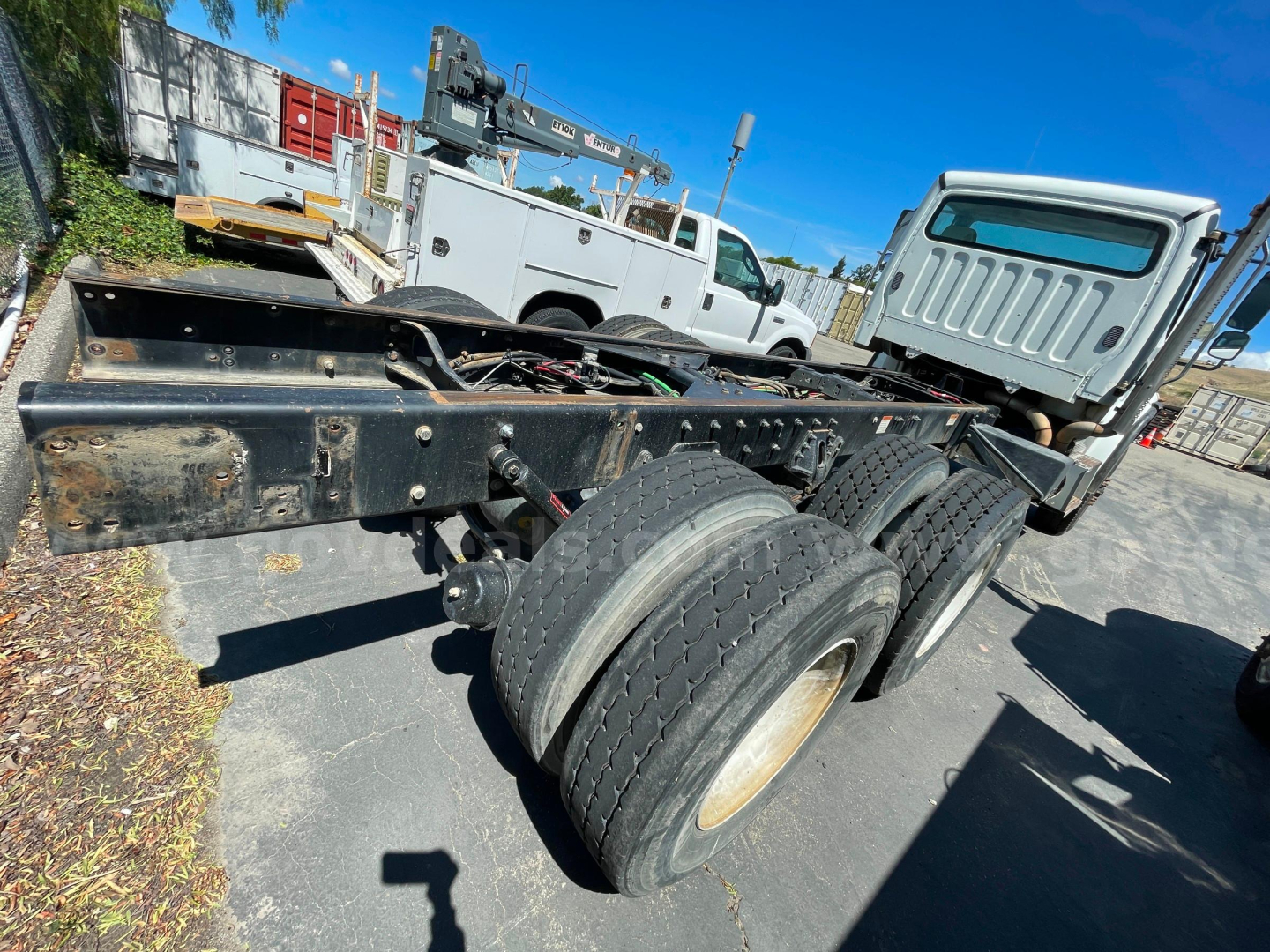 Freightliner M2 106 cab and chassis rear view showing dual rear axle and frame, front cab visible, with tires and undercarriage components.