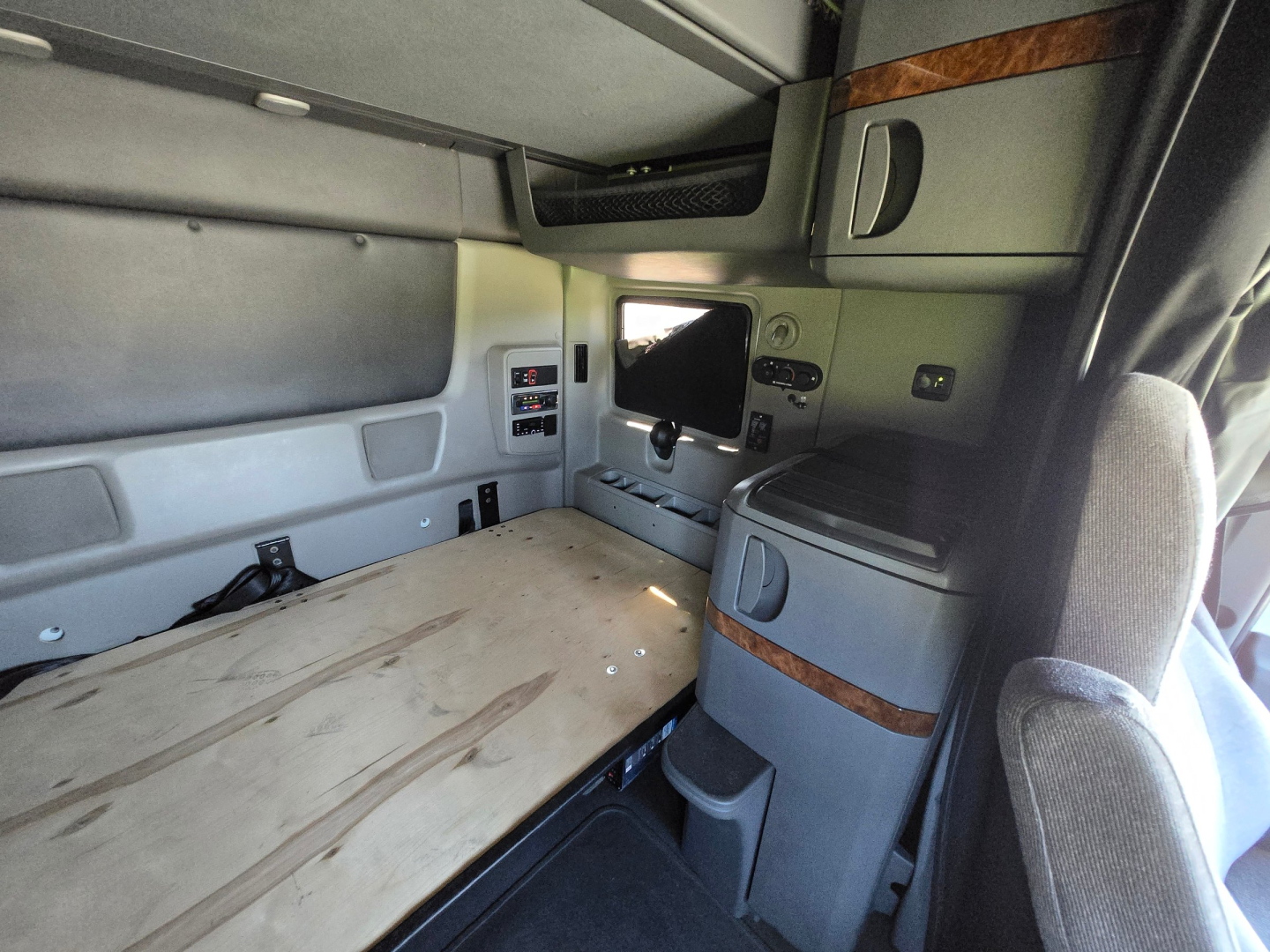 Interior sleeper cab of a 2021 International LT625 showing bunk bed platform and side cabinetry with small monitor and storage compartments.