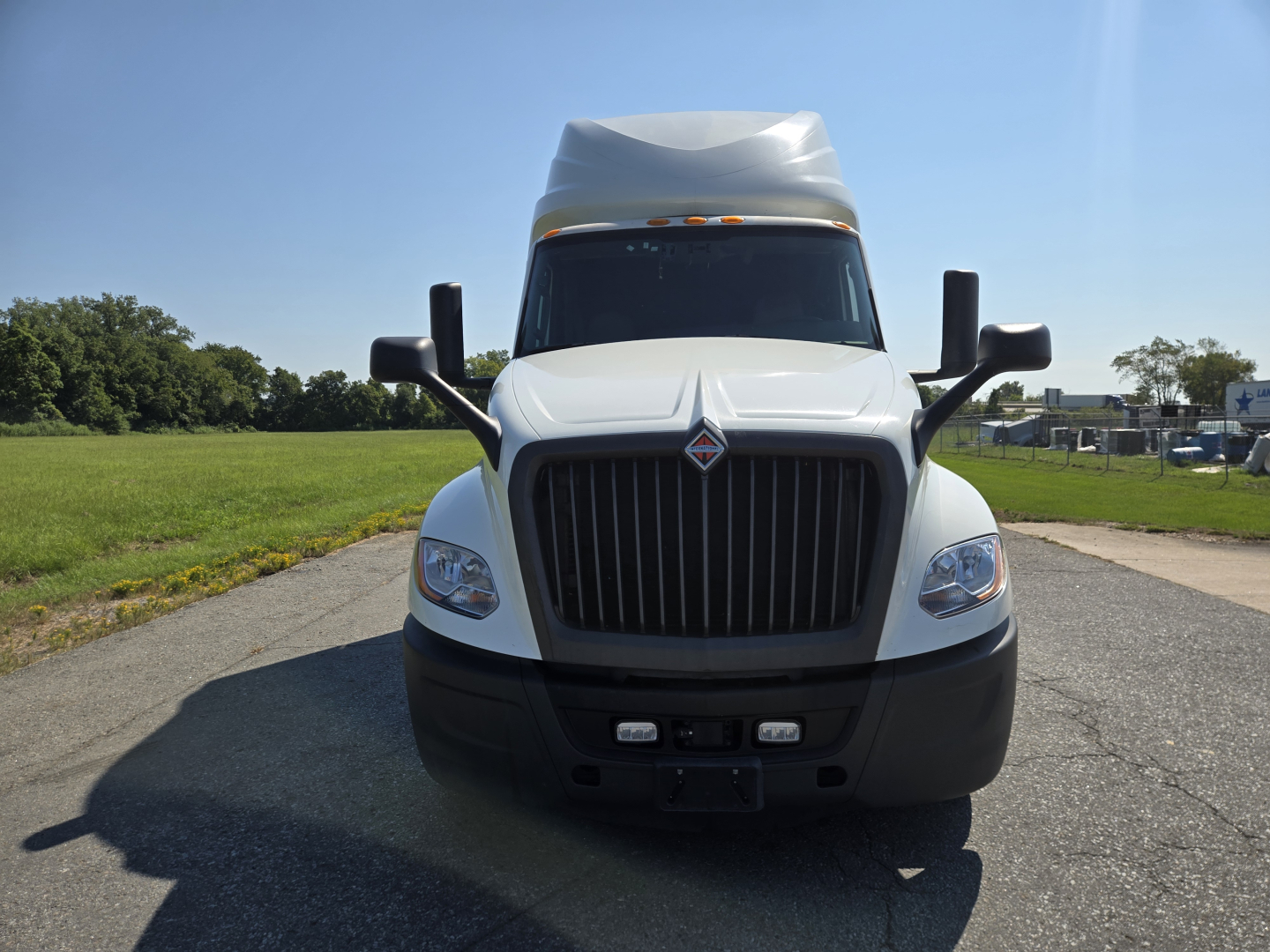 Front view of a white International LT625 truck with large grille, two side mirrors, and stacked headlights.