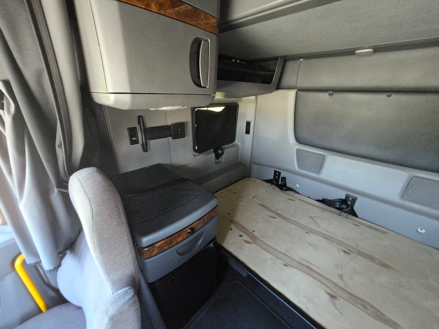 Interior cabin of a 2021 International LT625 sleeper truck showing bench/double bunk area with storage cabinet and overhead shelf.