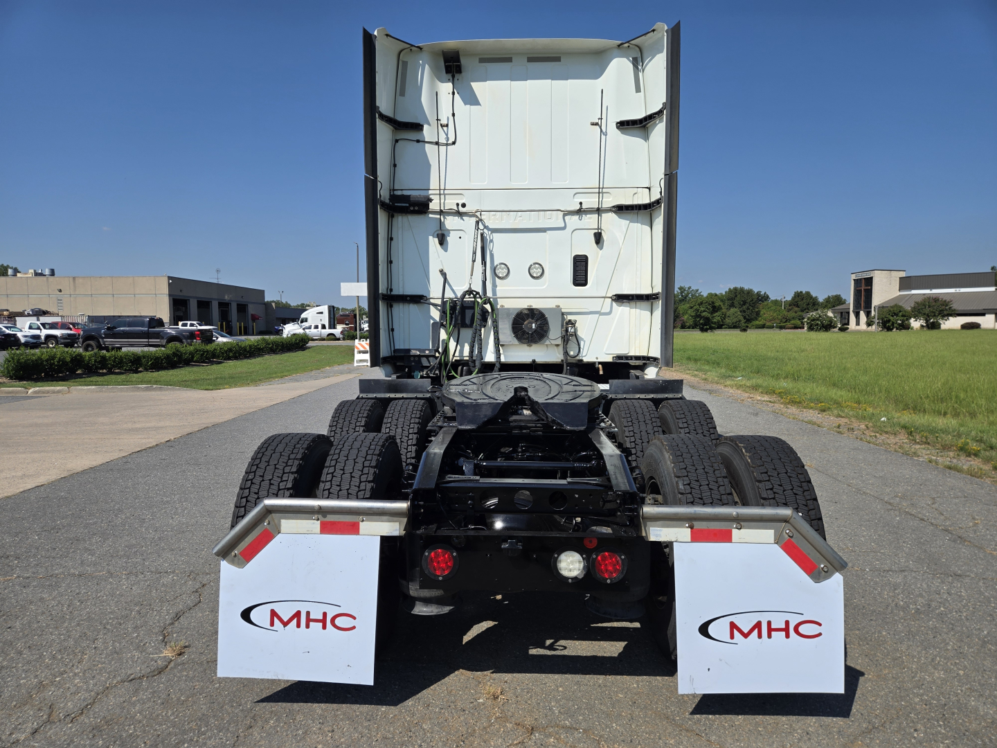 Rear view of a 2021 International LT625 truck chassis showing rear cab, dual rear axles, mud flaps with MHC logos, and loading area.