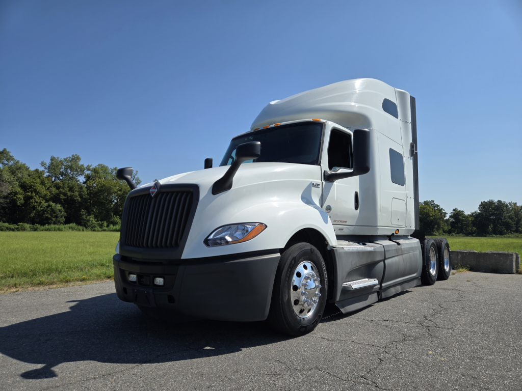 International LT Series tractor-trailer in white cab showing exterior with sleeper, front grille, and dual rear axles.