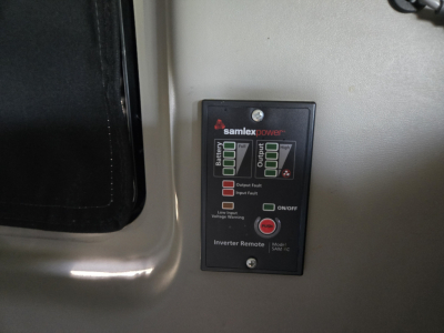 Truck interior showing Samlex Power inverter control panel with battery indicators and inverter remote display.