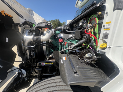 Volvo VHD64FT300 engine bay view showing coolant reservoir, hoses, and battery cables with green and red wiring visible.