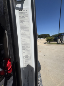 Volvo vehicle identification/label showing vehicle configuration fields and slots for model, engine, transmission, axle, etc. The tall vertical sticker on the door jamb lists blanks for vehicle data such as model, serial, engine, and other 