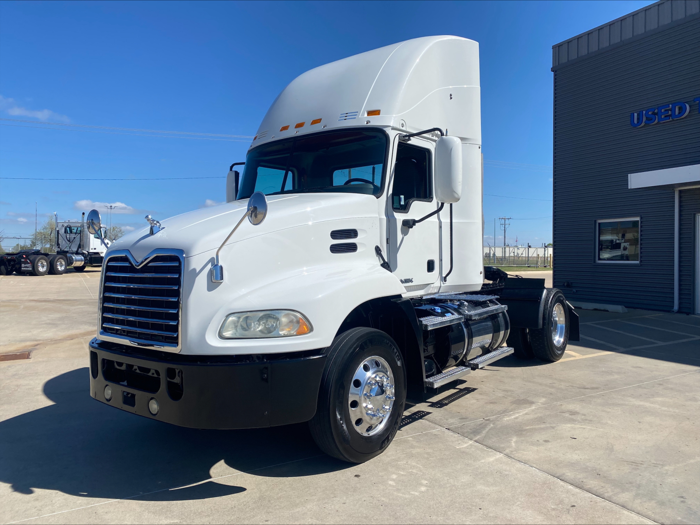 Truck cab of a white 2018 Mack CXU612 daycab with chrome grille and large sleeper fairing.