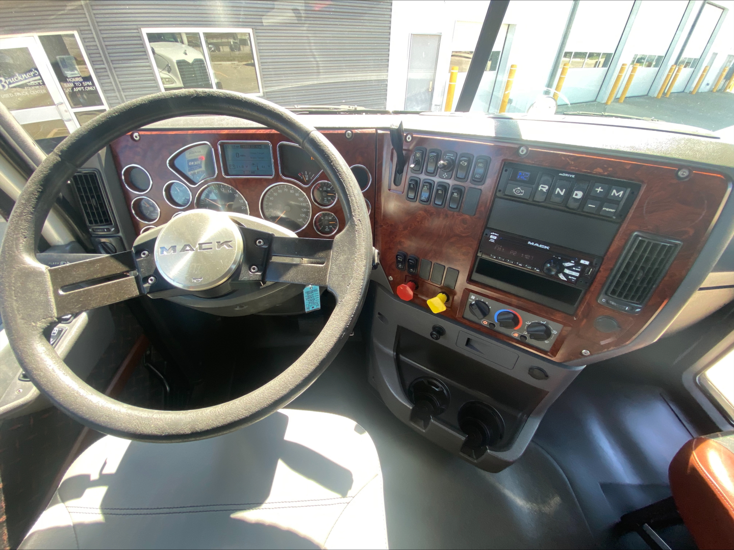 Mack CXU612 cab interior showing steering wheel, dashboard with gauges, and control panel.
