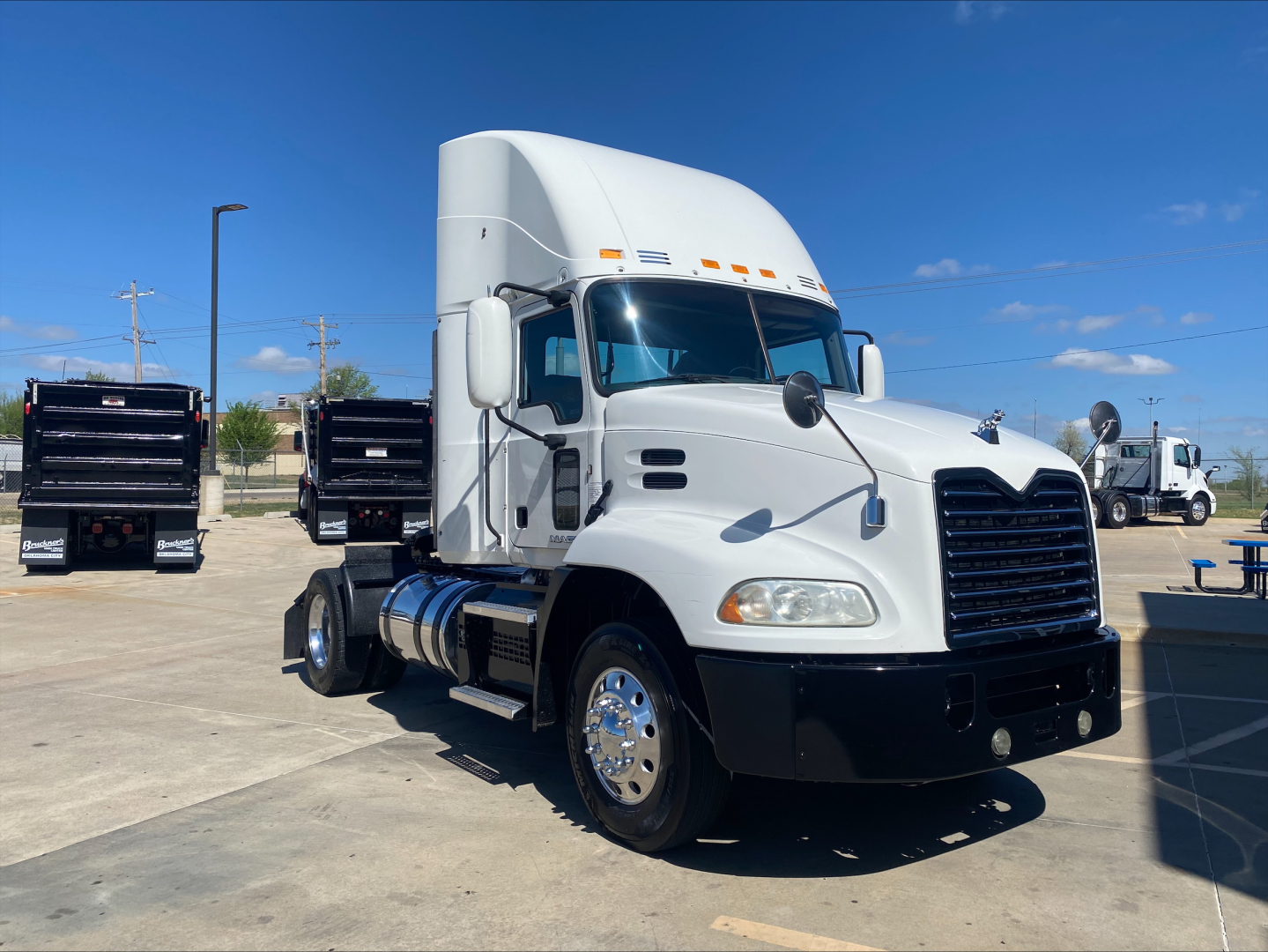Mack CXU612 sleeper cab truck in a lot showing front and side view with chrome wheels and white paint.