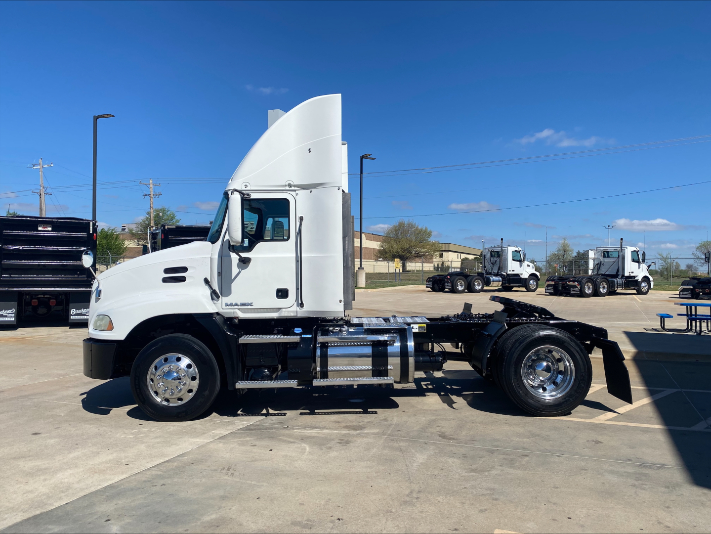 Mack CXU612 conventional daycab truck side view showing chassis and cab with white paint and chrome wheels.