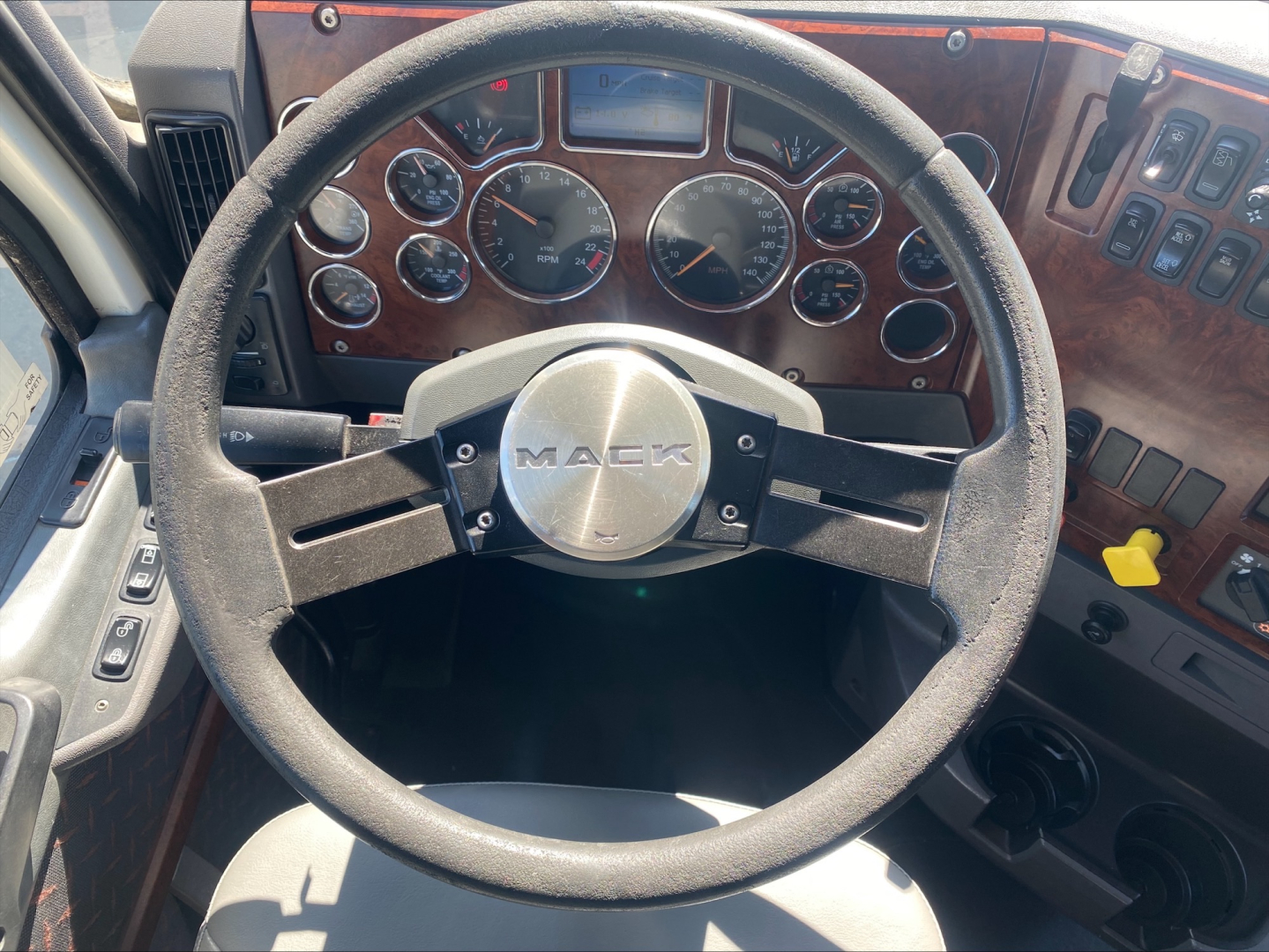 Mack CXU612 truck interior dashboard and steering wheel with wooden grain trim and multiple gauges visible.