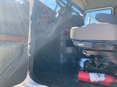 Truck cab interior showing Mack CXU612 dashboard and seat from driver side door angle. Visible controls and steering wheel.