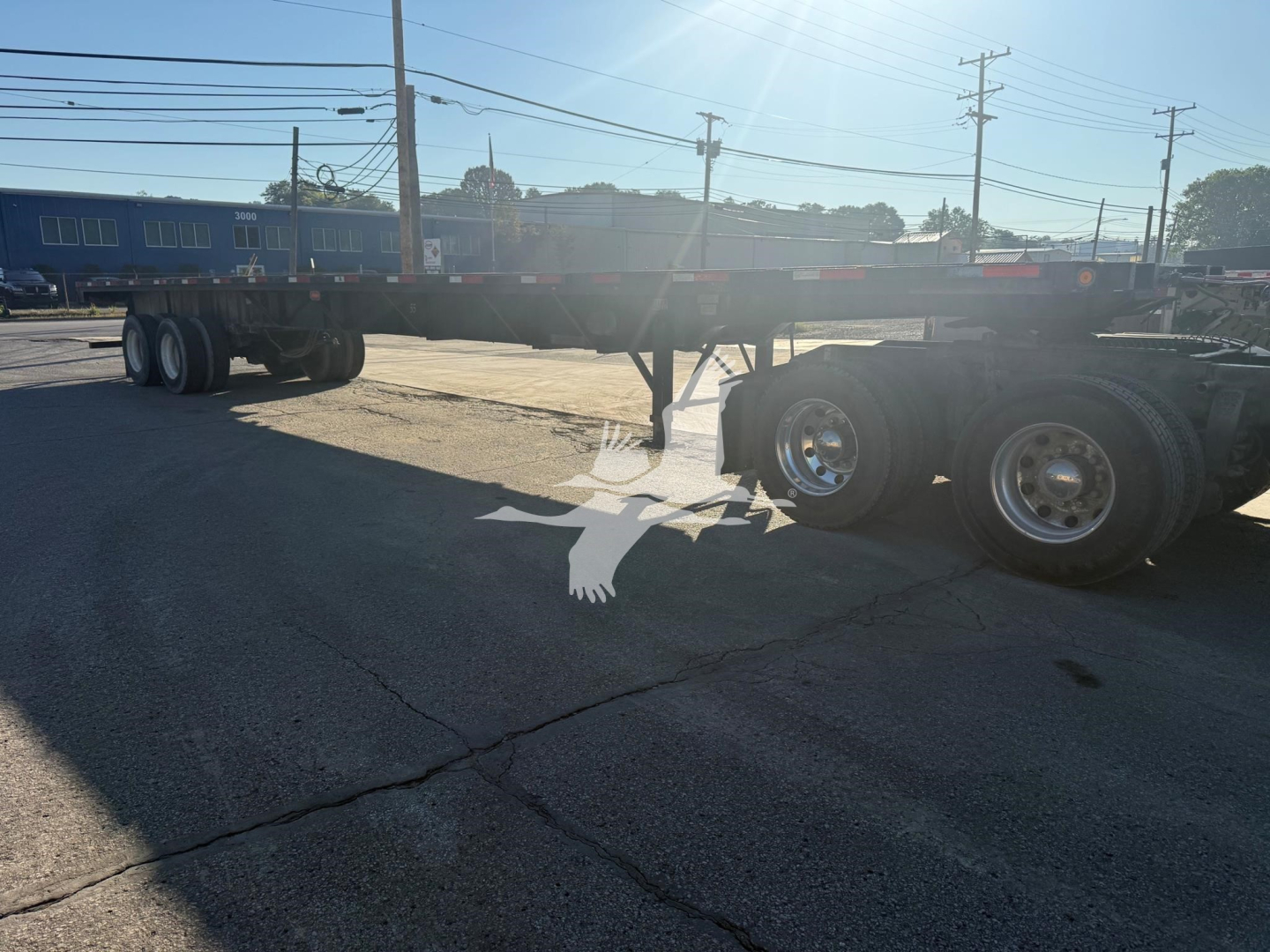Flatbed trailer showing Fontaine Xtp 4880Ss2 with dual rear axles and long frame under clear sky.