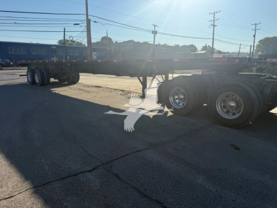 Flatbed trailer showing Fontaine Xtp 4880Ss2 with dual rear axles and long frame under clear sky.