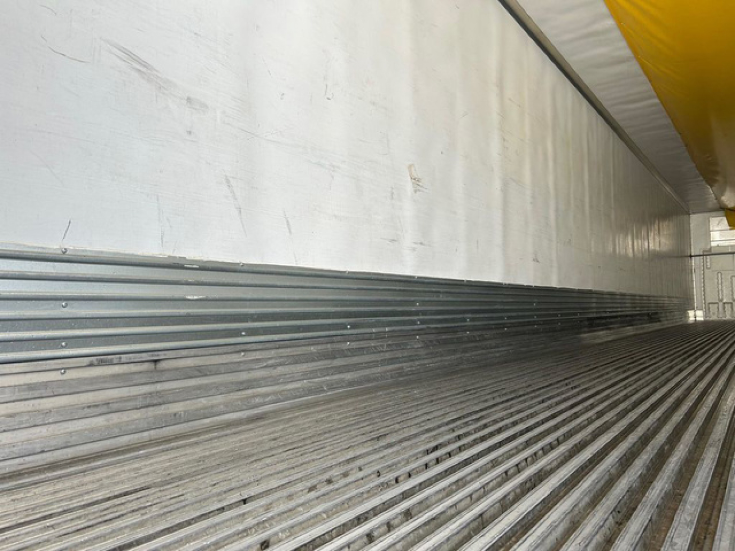 Trailer interior side showing corrugated floor and metal wall panels.