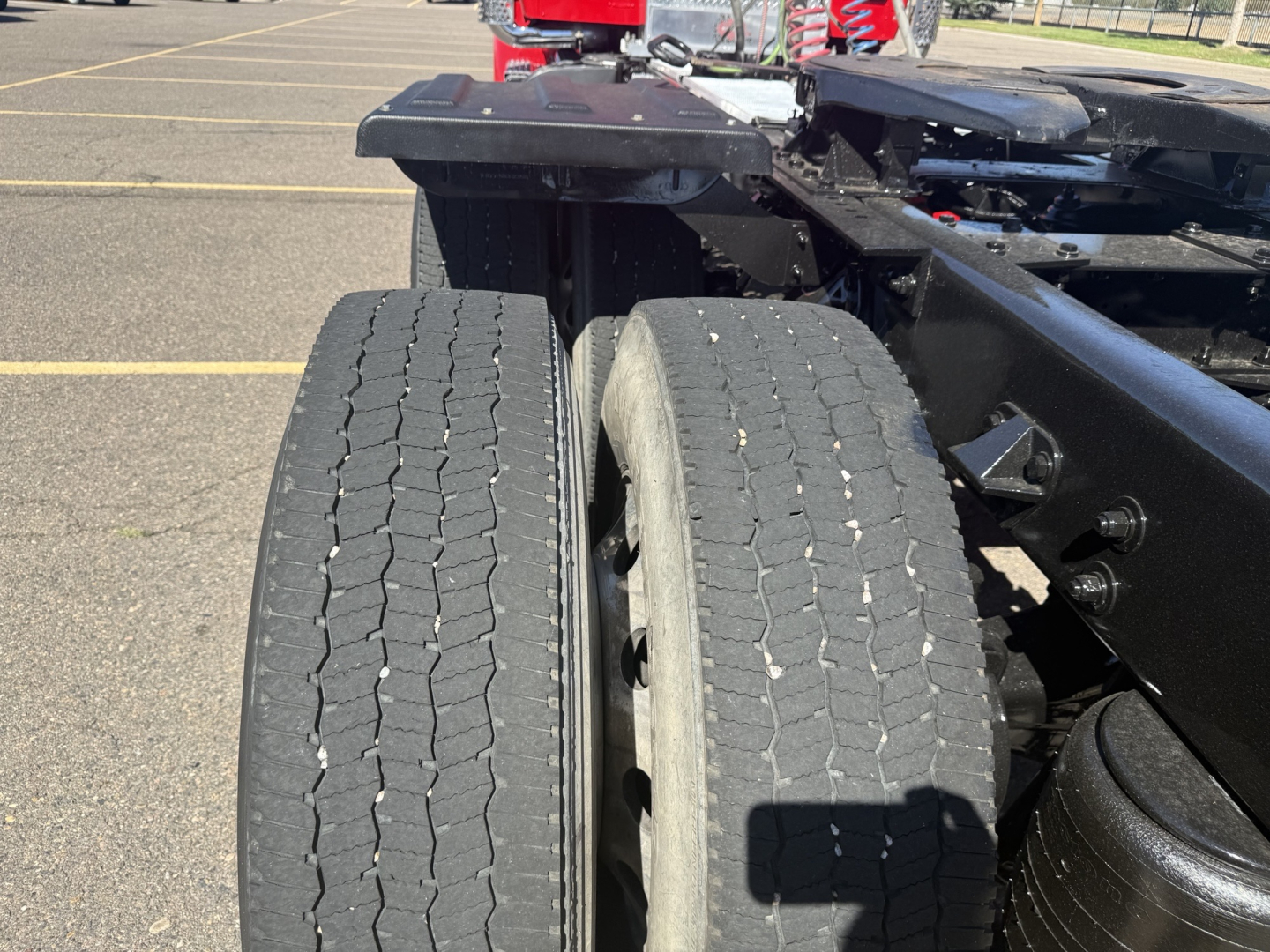 Kenworth T880 chassis with dual rear tires and fifth wheel area visible; portion of frame and suspension; parking lot background.
