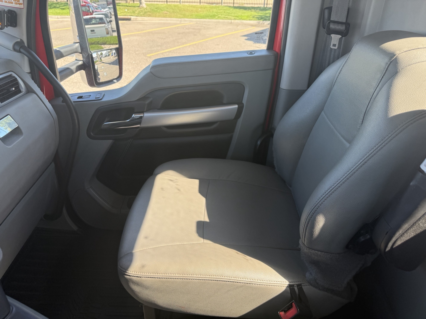 Kenworth T880 truck interior passenger seat and door panel showing gray fabric seat and armrest, window controls on door, light gray interior