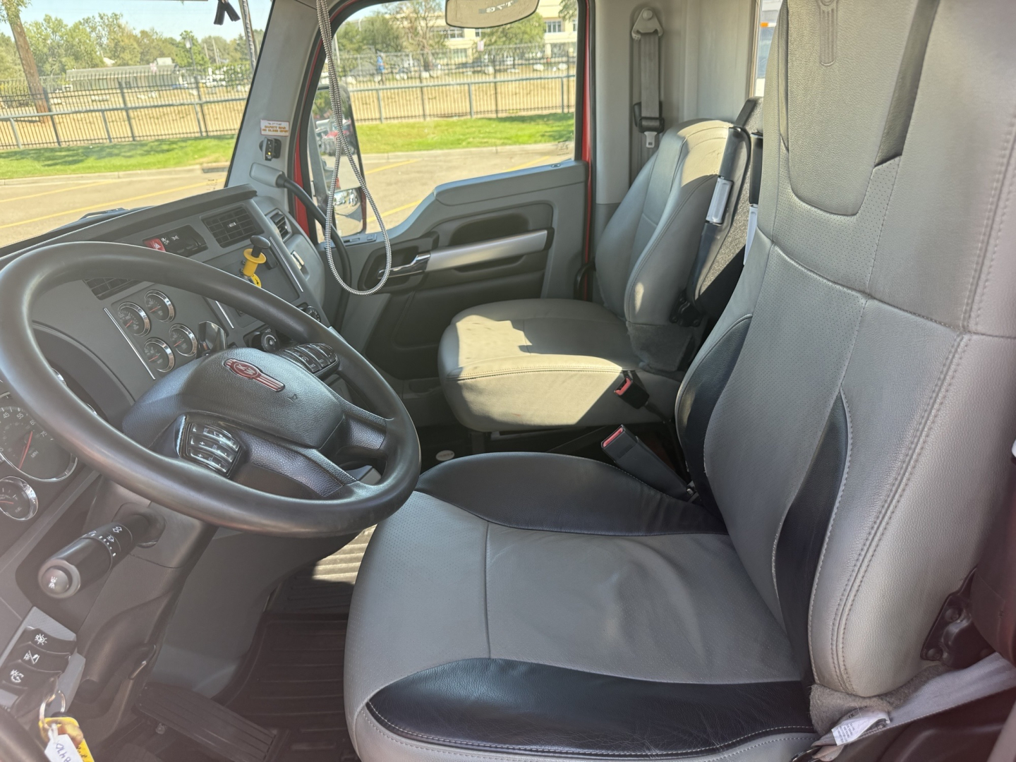 Kenworth T880 truck interior showing driver and passenger seats, steering wheel, and dashboard view.