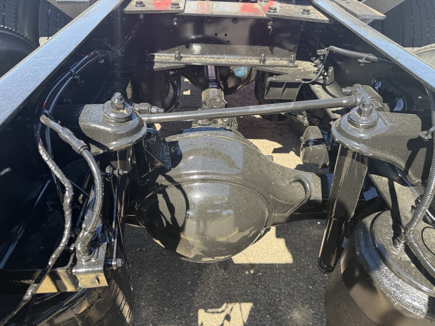 Kenworth truck rear view showing a solid rear axle differential and suspension links; visible components include drive axles, leaf springs, and air lines in a truck chassis.