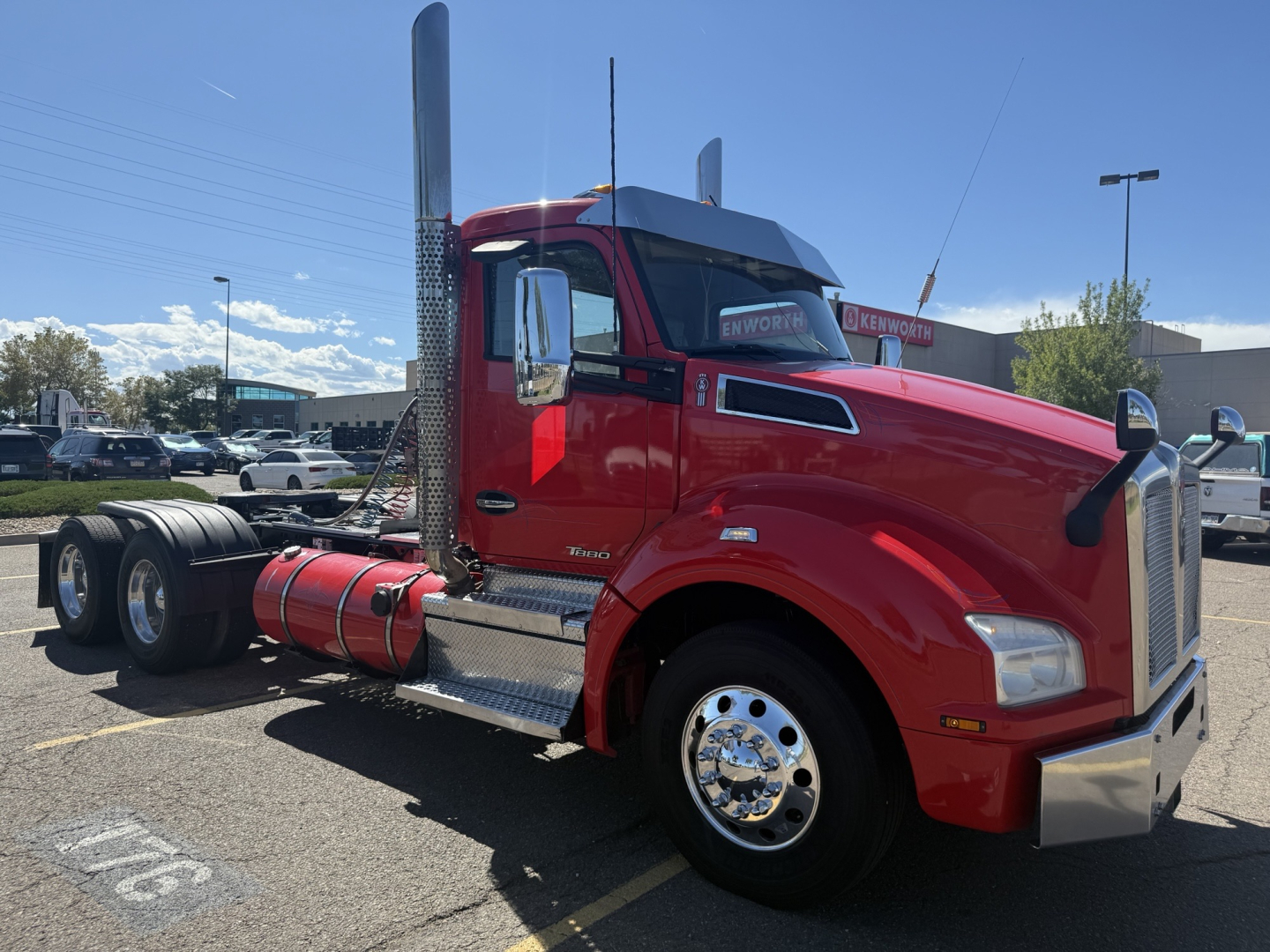 Kenworth T880 conventional daycab truck in red, side view showing chrome exhaust stack, air intake, fuel tank, and front bumper.