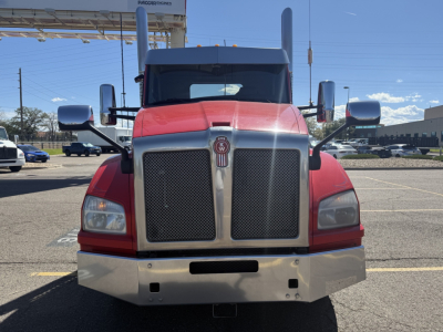 Kenworth T880 conventional daycab front view showing large grille, shiny chrome bumper, red cab, two side mirrors, and Kenworth emblem.