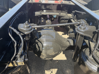 Kenworth truck rear view showing a solid rear axle differential and suspension links; visible components include drive axles, leaf springs, and air lines in a truck chassis.