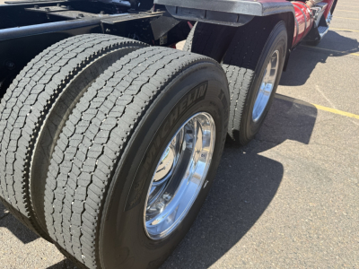 Kenworth T880 truck rear dual tires and wheel wells with chrome rims and red chassis side profile visible.
