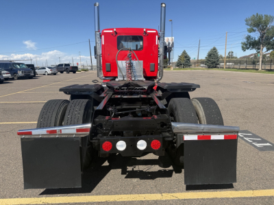 Kenworth truck rear view showing chassis and dual rear wheels, red sleeper cab, black mud flaps, and five rear lights.