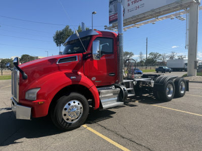 Kenworth T880 truck with red cab in a lot, front left view; visible text includes no clear stickers in cab.