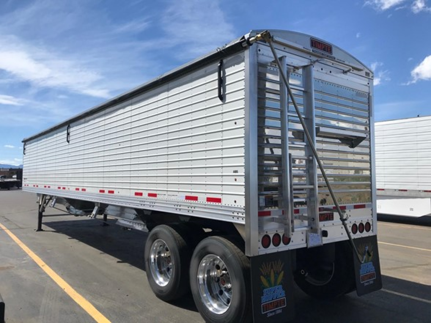 Trailer rear view showing Timpte Super Hopper aluminum end dump with dual rear doors, ladder, and twin axles.