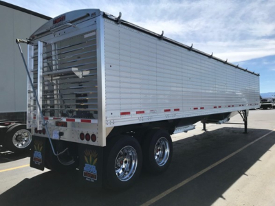 Timpte Super Hopper trailer side view showing aluminum hopper, dual rear axles, and rear gate with hydraulic latches.