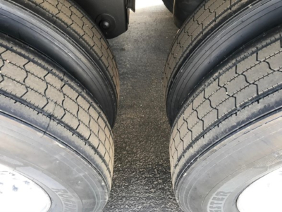 Trailer tires visible from a close-up between dual axles, tread pattern and sidewalls in view.