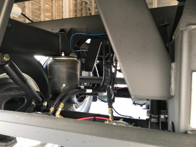 Hopper trailer undercarriage with hydraulic lines and frame components visible.